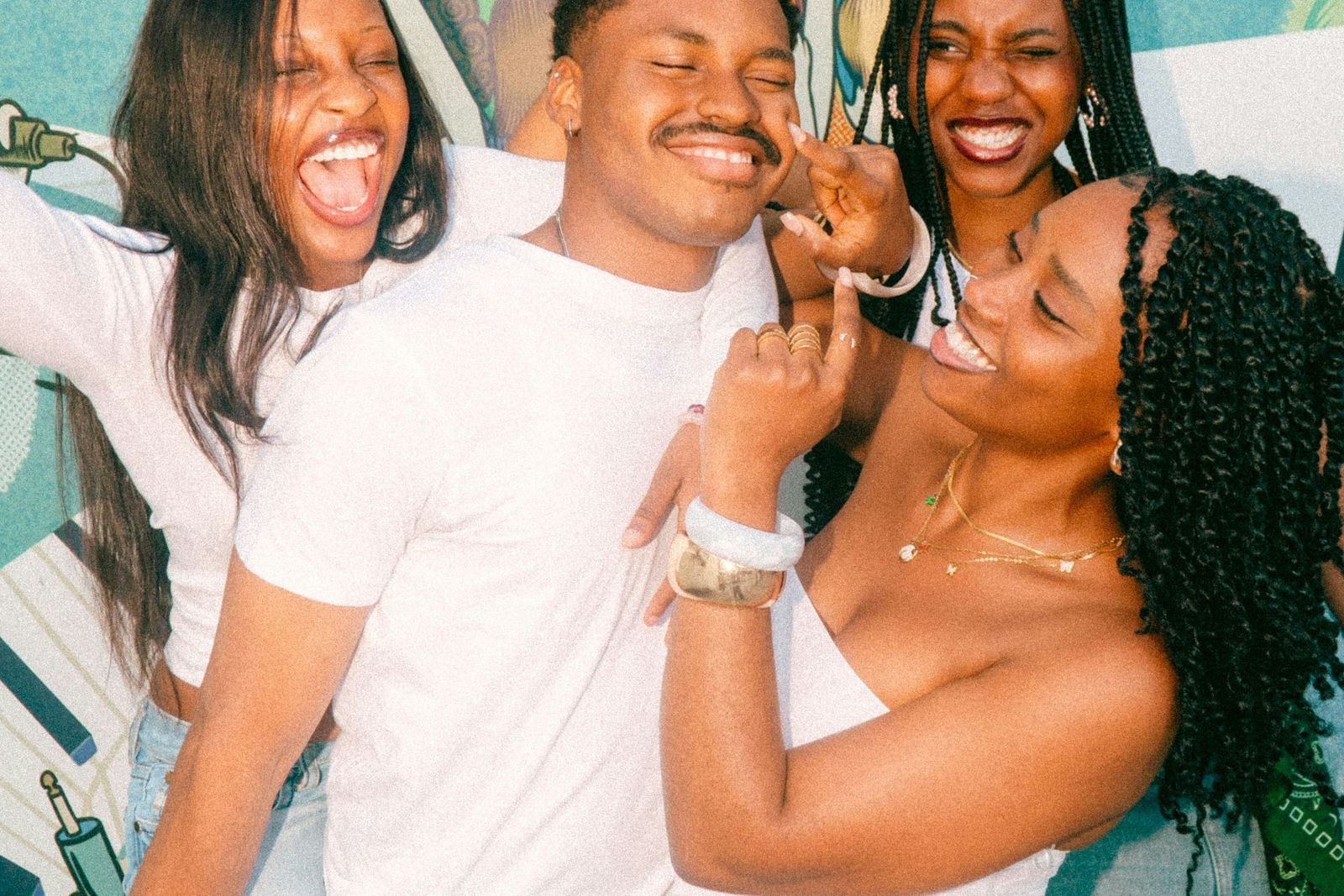 Four friends laughing together, arms around each other.